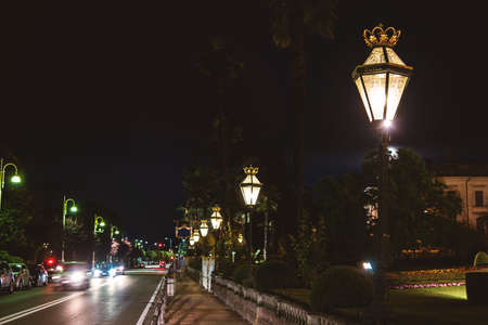 Cars in town at night. Street lamps and park. Discover the beauty of Stresa.の写真素材