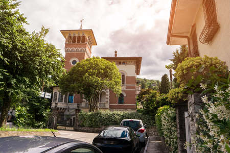 Classic building and trees. Cars parked near house. Historic landmark in Stresa.の写真素材
