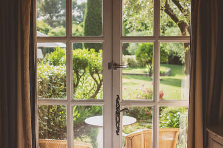 Nature behind the door. White frames with glass panels. Mansion with a garden.