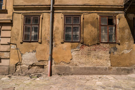 Wall of damaged building. Old dirty windows. Abandoned and forgotten.の写真素材