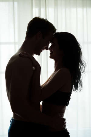 Couple smiling in the dark. Man and woman near window. Run away from the world.の写真素材