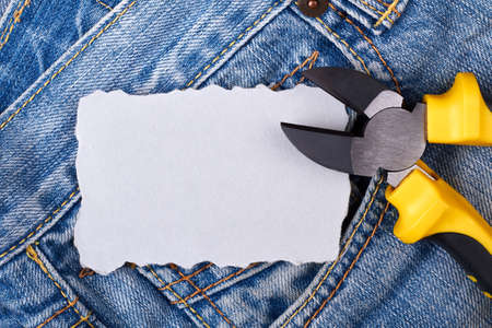 Blank paper and pliers. Paper piece in jeans pocket. Write your own work plan.の写真素材
