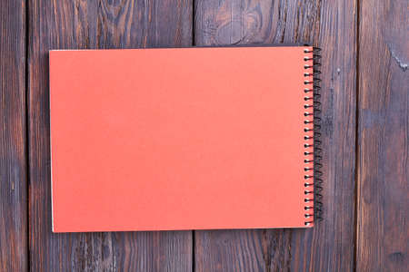 Notebook with spiral on wood. Peach color notepad on table. Equipment for studying.の写真素材