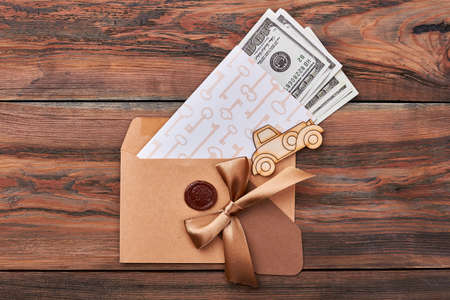 Money in envelope with seal. Key print paper near bow. Money is base of economy.