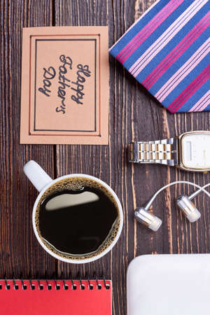 Coffee cup and greeting card. Notepad and earphones on wood. Start your day with coffee.の写真素材