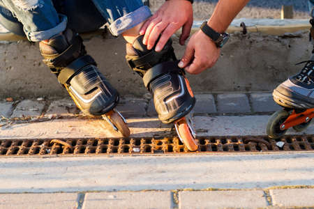 Male hands touching rollerblades. Black inline skates. New sports equipment.の写真素材