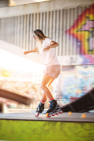 Girl on rollerblades. Young woman on blurred background. Ride with grace.の写真素材