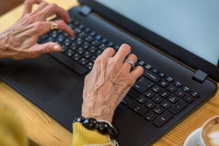 Old womans hands and laptop. Pc keyboard of black color. Know more about modern technologies.の写真素材