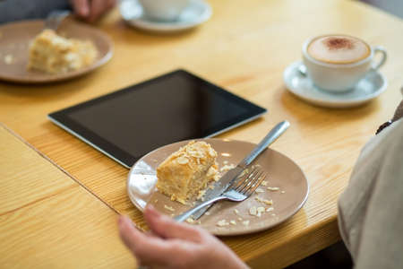 Cake and cutlery on plate. Tablet on a wood table.の写真素材