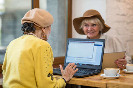 Elderly ladies with laptop. Coffee cup near notebook pc. Compare speed of internet connection.の写真素材