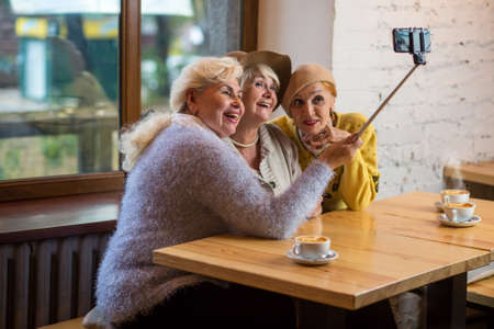 Selfie of ladies in cafe. Senior women smiling. Years pass but friends remain.の写真素材