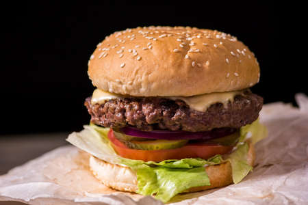 Burger on black background. Grilled meat and fresh vegetables.の写真素材