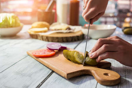 Knife cutting pickled cucumber. Sliced vegetables on wooden board. Ingredient for salty salad.の写真素材
