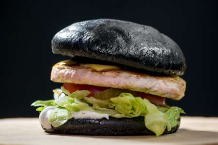 Burger with black bun. Hamburger on dark background.の写真素材