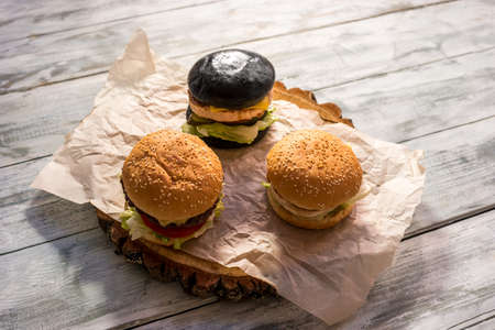 Three burgers on wooden background. Hamburgers with sesame buns. Tasty food at lowest price.の写真素材