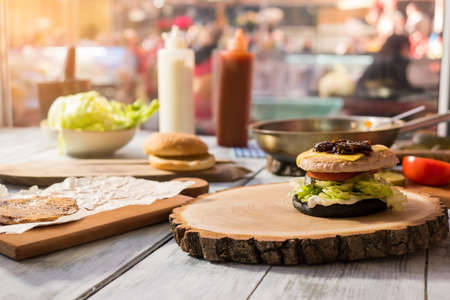Burger ingredients on wood board. Meat, vegetables and bun. Layer by layer.の写真素材