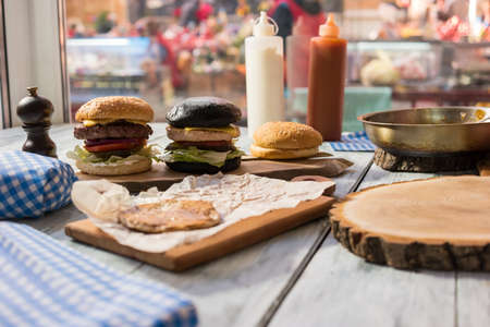 Wood board with two burgers. Junk food on wooden table. Best cheeseburgers in town.の写真素材