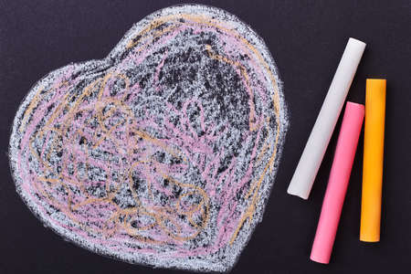 Doodle heart on black background. Colorful chalk sticks and heart. Simple but creative surprise.の写真素材