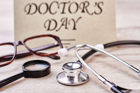 Loupe, stethoscope and greeting card. Spectacles on wooden surface.の写真素材