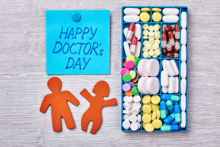 Medicine in container. Stickmen on wooden surfice. Congratulation for a doctor.