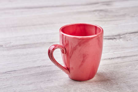 Empty mug on wooden backdrop. Pink ceramic cup.の写真素材