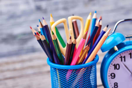 Stationery and alarm clock. Colourful pencils and scissors. Time for art class.の写真素材