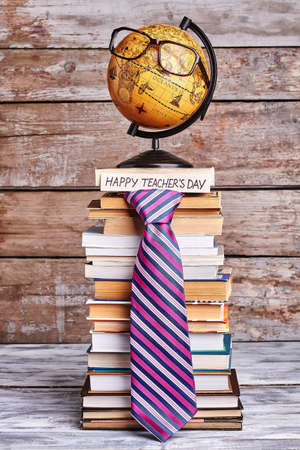 Glasses on globe and tie. Stack of books and card. Congratulate geography teacher.の写真素材