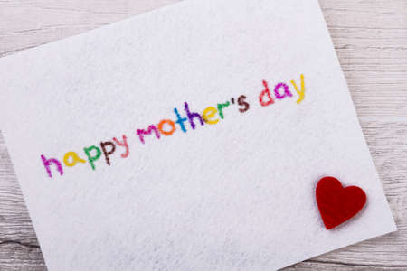 Happy Mothers Day greeting card. Fabric heart near inscription. Make colorful congratulation. Prepare a nice surprise.の写真素材