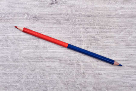 Colored pencil on wooden background. Red and blue pencil.