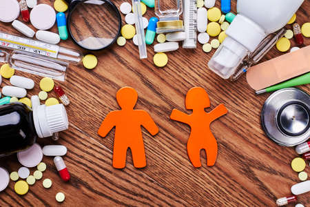 Pills, stickmen on wooden backdrop. Medical center protects your health.の写真素材