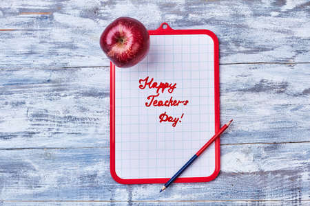 Clipboard, pencil and apple. Brief congratulation to Teachers Day.