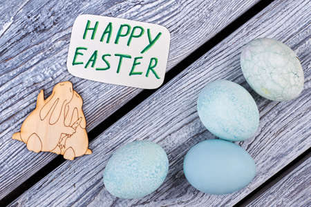 Dyed eggs on grey wood. Greeting card and plywood bunnies. Easter congratulatory composition.