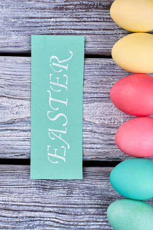 Turquoise Easter card and eggs. Vertical egg row on wood.の写真素材