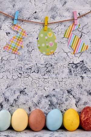 Paper cutouts, rope and clothespins. Row of painted eggs. Easter home decor ideas.の写真素材