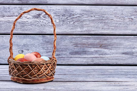 Basket with eggs on wood. Wicker Easter basket.