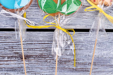 Cookies wrapped in plastic. Biscuits with bows on wood. Birthday party treats ideas.