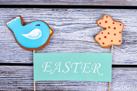 Two cookies and Easter card. Biscuits on gray wooden background. Homemade treats for kids.