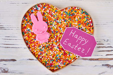 Sweets and Happy Easter card. Heart box on wooden background. Easter gift for girlfriend.の写真素材