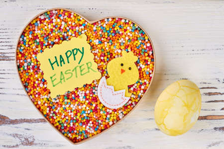 Easter greeting card and sweets. Dyed egg on white wood. Cute easter gifts for girlfriend.