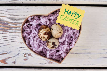 Quail eggs, Happy Easter card. Heart box on wooden background. Love and faith.の写真素材