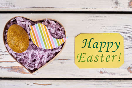 Easter gift box, sparkly egg. Greeting card on wooden surface.