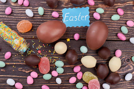 Easter card and scattered sweets. Candies on dark wood background. Homemade Easter candy recipes.