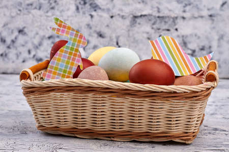 Easter basket with paper cutouts. Pile of dyed chicken eggs.