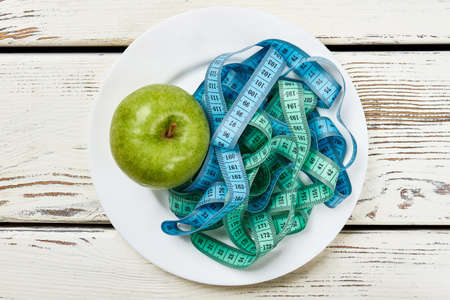Apple, plate and measuring tape. Eat right and be bright.の写真素材