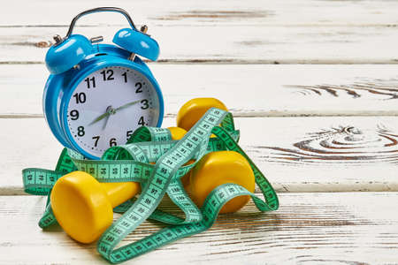 Alarm clock and measuring tape. How to build good health.の写真素材