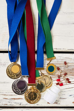 Medals and pills on wood. Prohibited drugs for athletes.の写真素材