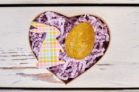 Box with shiny Easter egg. Light purple shredded paper. Make a special Easter present.