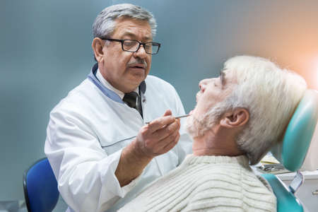 Old man at the dentist. Dental doctor is examining patient. Deep knowledge of dentistry.の写真素材
