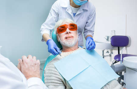 Dentist with elderly patient. Senior man in dental chair.の写真素材