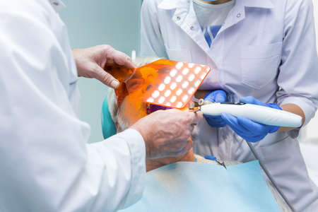 Stomatologist using ultraviolet light. Hands of dentists working.の写真素材